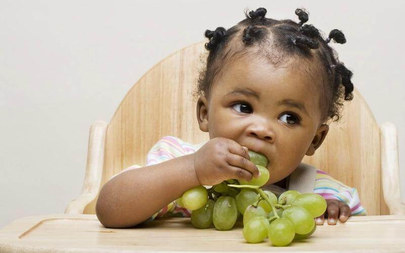 Young dietitian eating grapes